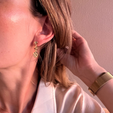 Close-up of a person wearing gold earrings with a neutral background